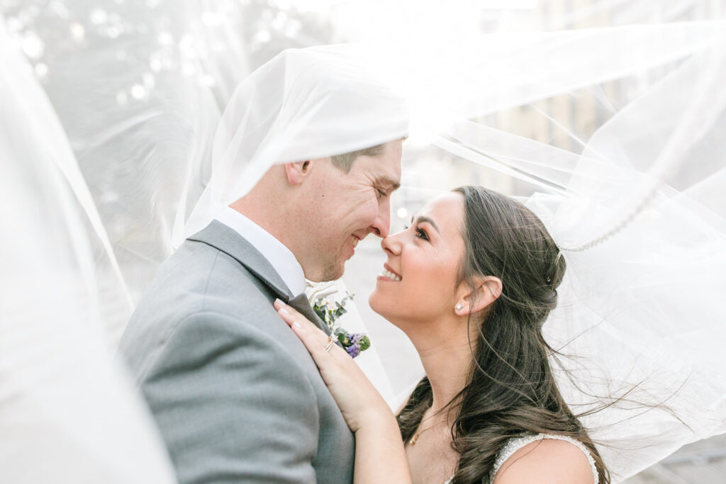 bride and groom pose under bride's veil