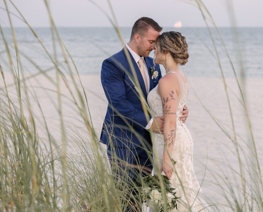 Newlyweds embrace on Biloxi Beach at sunset