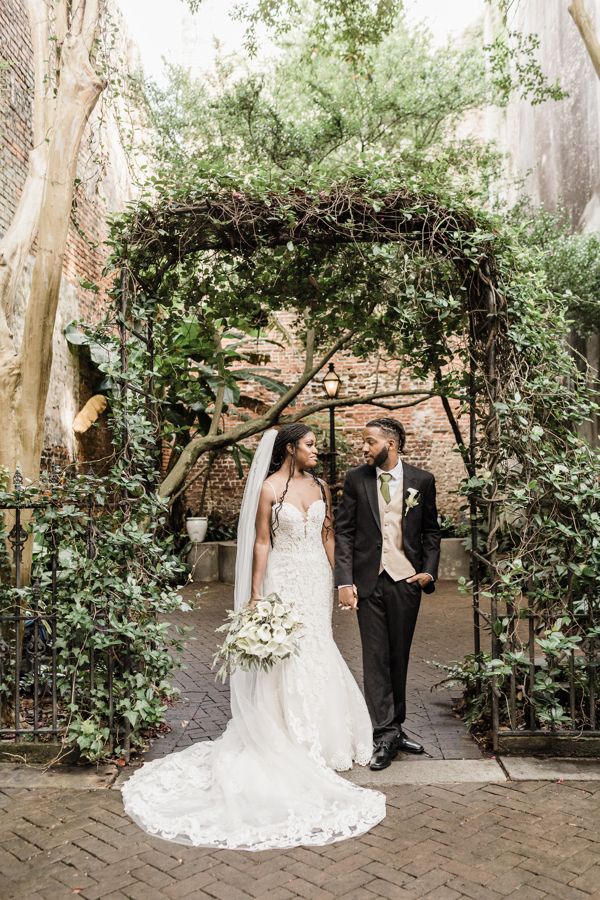 Newlyweds pose under a vine covered trellis at the Pharmacy Museum in New Orleans