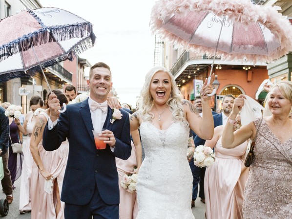 Newlyweds hold decorative umbrellas during second line parade through the French Quarter