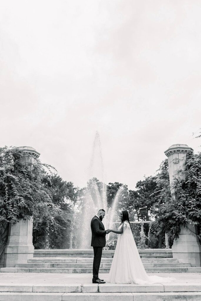 bride and groom stand in front of popp fountain