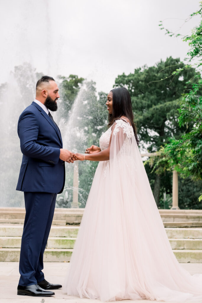 bride and groom hold hands during wedding ceremony at popp fountain